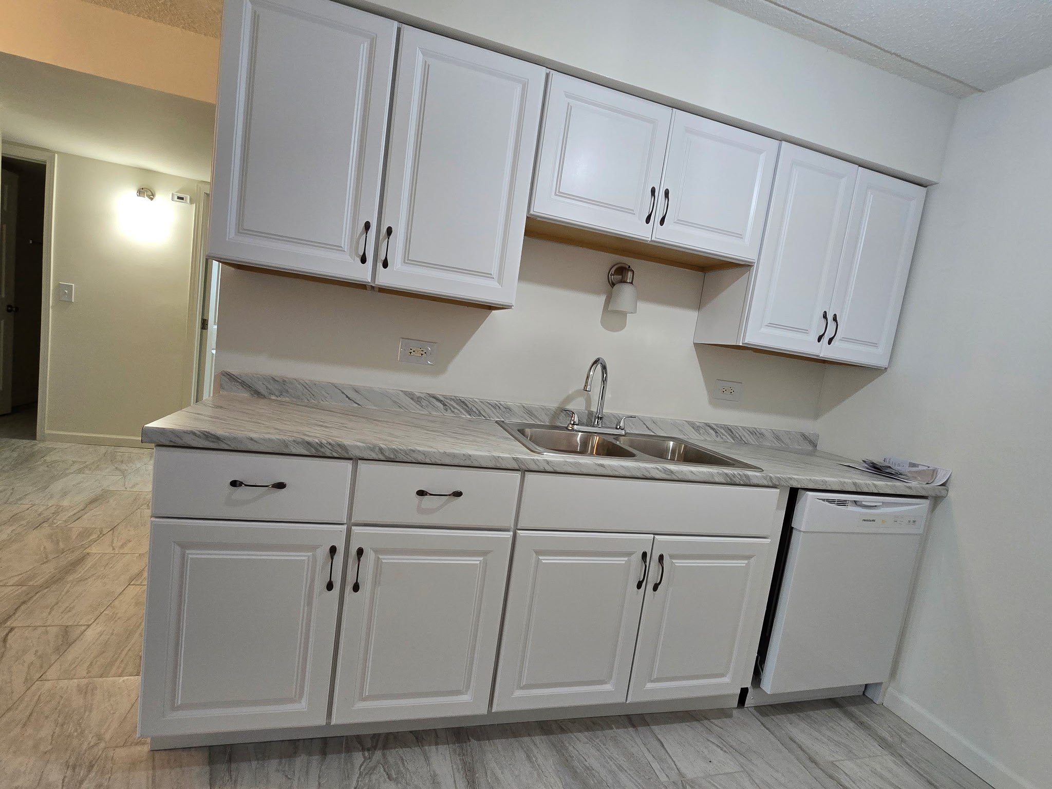 A kitchen with white cabinets and a marble countertop.